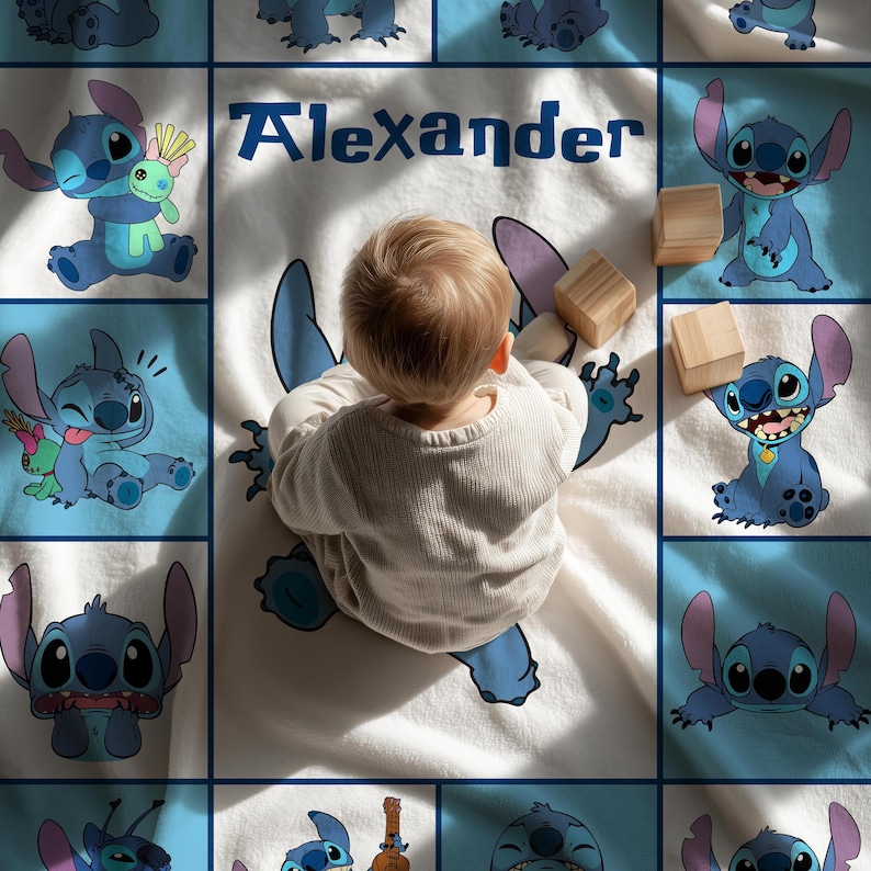 May include: A baby blanket featuring a blue cartoon character design and the name "Alexander" in blue text. The blanket has a white background with blue squares and cartoon character illustrations. Wooden blocks are also present.