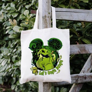 Op de afbeelding: Cr&egrave;me canvas draagtas met een groene afbeelding van een personage met Mickey Mouse oren, een spinnenweb en de tekst "Let's Oogie Boogie". Het ontwerp bevat een grafsteen en andere Halloween-thema-elementen.