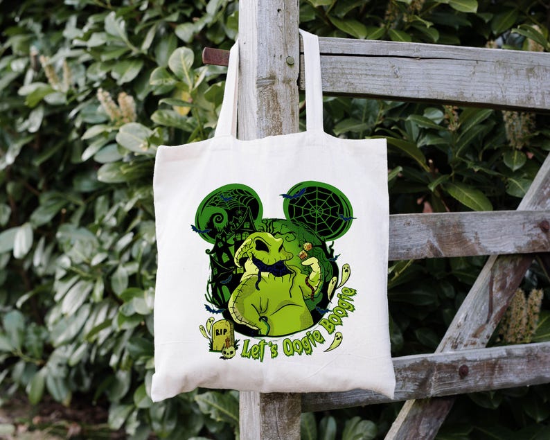 Op de afbeelding: Cr&egrave;me canvas draagtas met een groene afbeelding van een personage met Mickey Mouse oren, een spinnenweb en de tekst "Let's Oogie Boogie". Het ontwerp bevat een grafsteen en andere Halloween-thema-elementen.