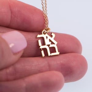 May include: Gold necklace with a pendant featuring the Japanese kanji character for "peace".