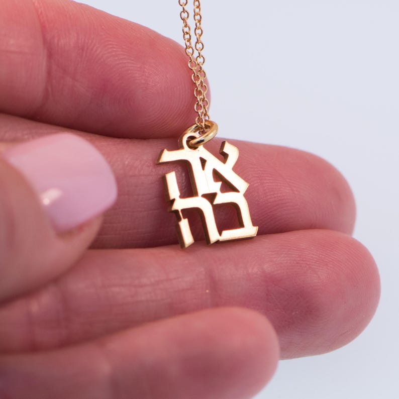 May include: Gold necklace with a pendant featuring the Japanese kanji character for "peace".