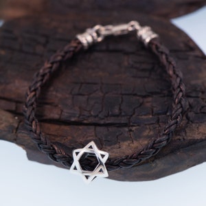 May include: A brown leather braided bracelet with a silver Star of David charm.