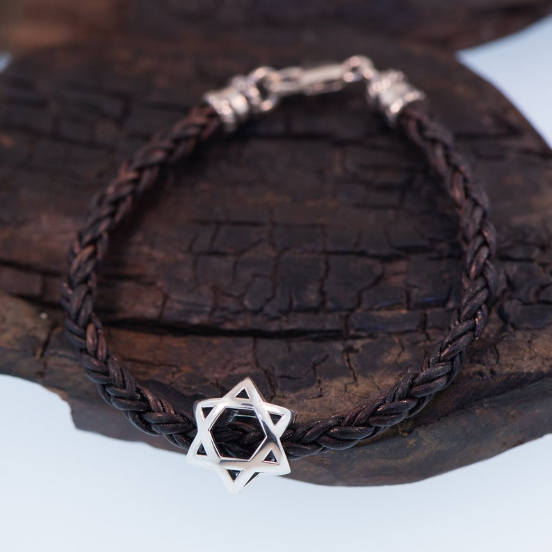 May include: A brown leather braided bracelet with a silver Star of David charm.