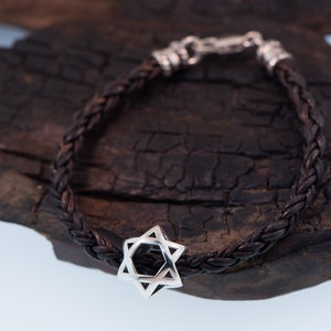 May include: A brown leather braided bracelet with a silver Star of David charm.