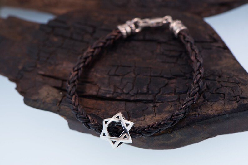 May include: A brown leather braided bracelet with a silver Star of David charm.