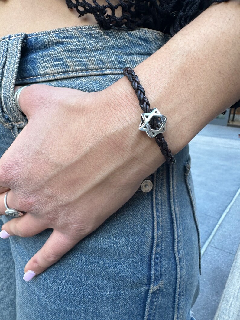 May include: A brown leather braided bracelet with a silver Star of David charm.