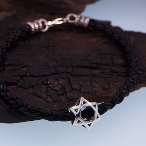 May include: A black leather braided bracelet with a silver Star of David charm.