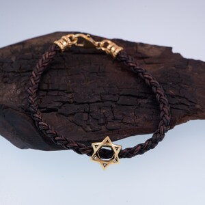 May include: A brown leather braided bracelet with a gold Star of David charm.
