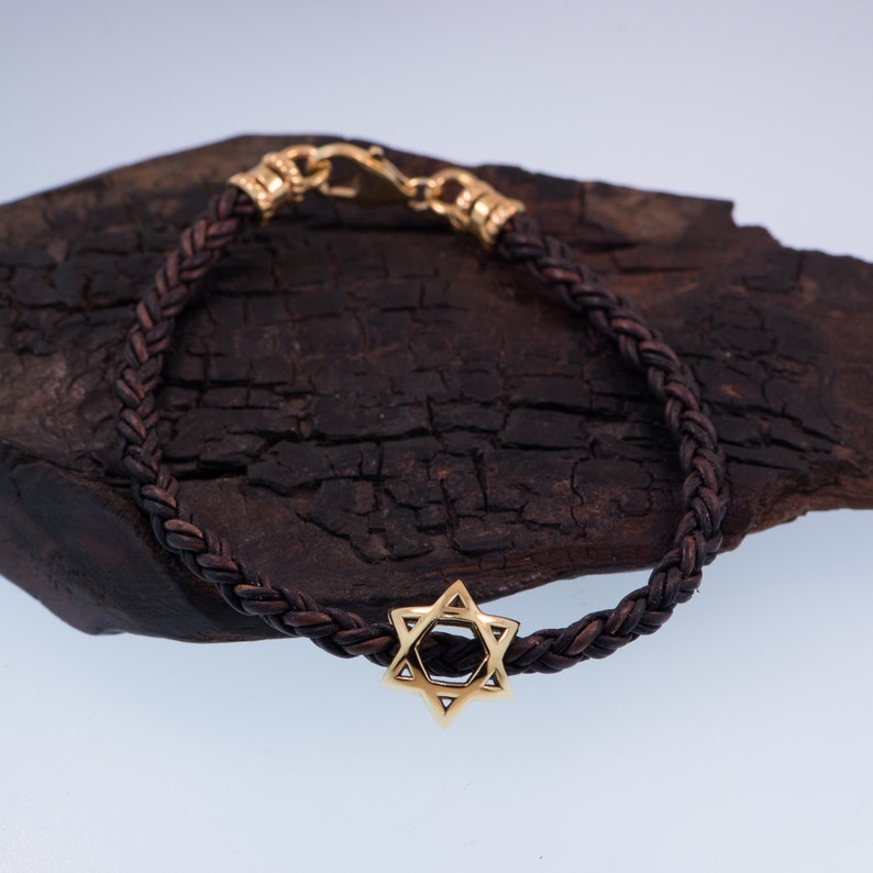 May include: A brown leather braided bracelet with a gold Star of David charm.