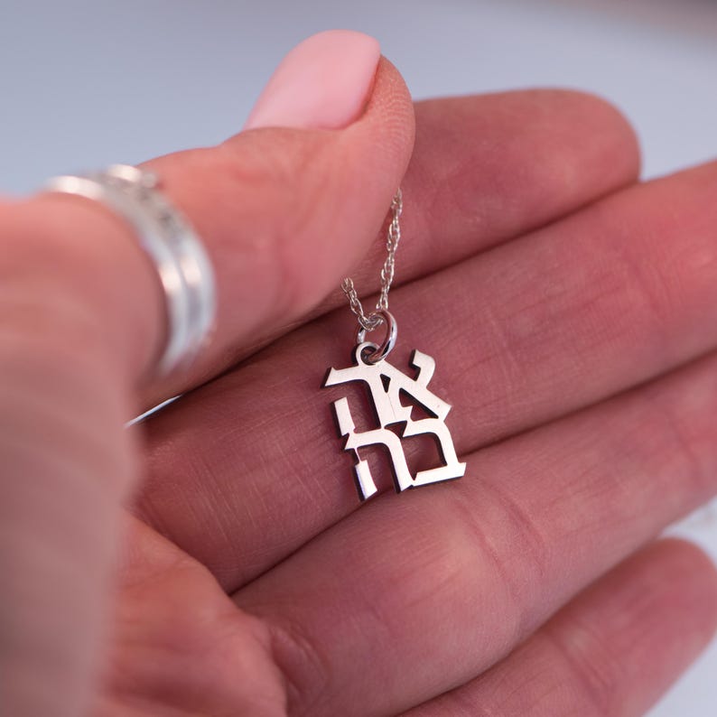 May include: A silver necklace with a pendant featuring the Hebrew word "Chai" in a stylised font.