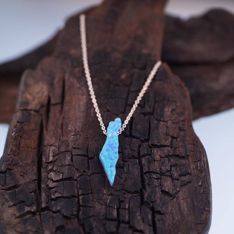 Op de afbeelding: Een zilveren ketting met een blauwe opaal hanger in de vorm van de omtrek van Isra&euml;l.