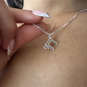 Peut inclure: Un collier argent&eacute; avec un pendentif d&eacute;licat en forme de la lettre "R". Le pendentif est suspendu &agrave; une fine cha&icirc;ne. Le collier est pr&eacute;sent&eacute; sur un fond de teint.