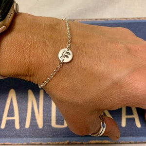 May include: A silver chain bracelet with a round charm featuring a musical note design.