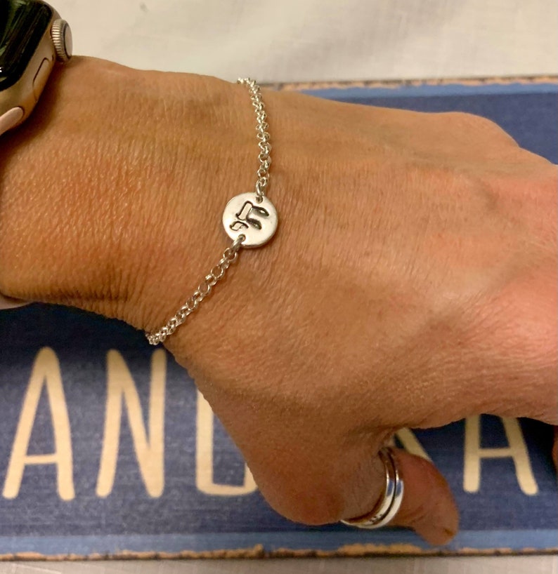 May include: A silver chain bracelet with a round charm featuring a musical note design.