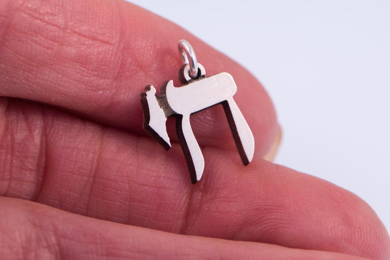 Puede incluir: Un amuleto de plata con forma de la letra hebrea Jai, que simboliza la vida.