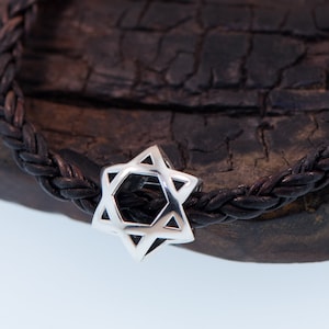 May include: A silver Star of David charm on a black leather braided bracelet.