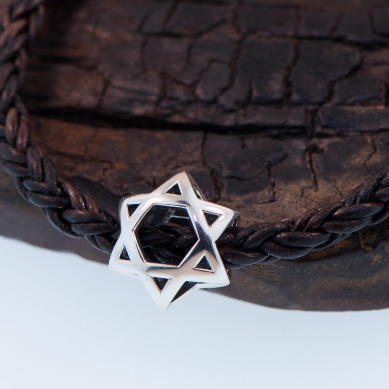 May include: A silver Star of David charm on a black leather braided bracelet.