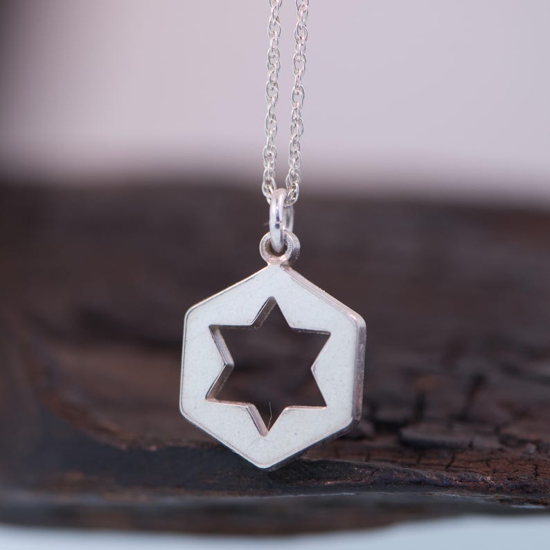 May include: A silver necklace with a hexagonal pendant featuring a cut-out Star of David.