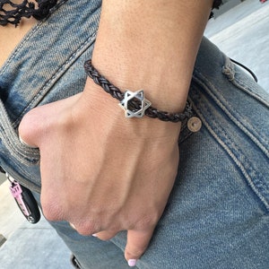 May include: A brown leather braided bracelet with a silver Star of David charm.