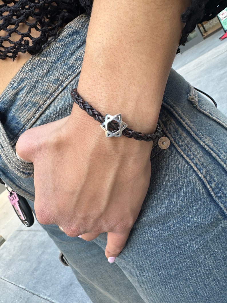 May include: A brown leather braided bracelet with a silver Star of David charm.