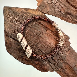 May include: A brown leather bracelet with silver beads. The beads are engraved with Hebrew letters and a Star of David.