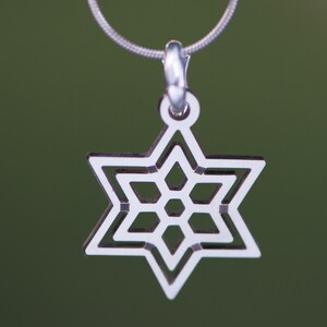 May include: A silver-colored pendant necklace featuring a Star of David design. The pendant is a six-pointed star with a detailed, openwork pattern. The necklace has a delicate chain and a simple clasp.