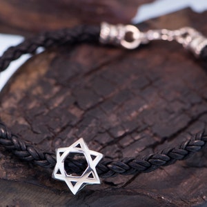 May include: A black leather braided bracelet with a silver Star of David charm.