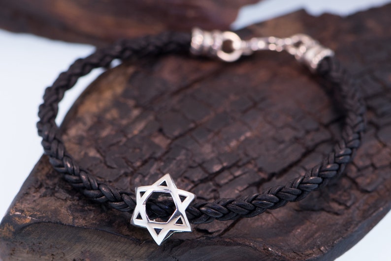 May include: A black leather braided bracelet with a silver Star of David charm.