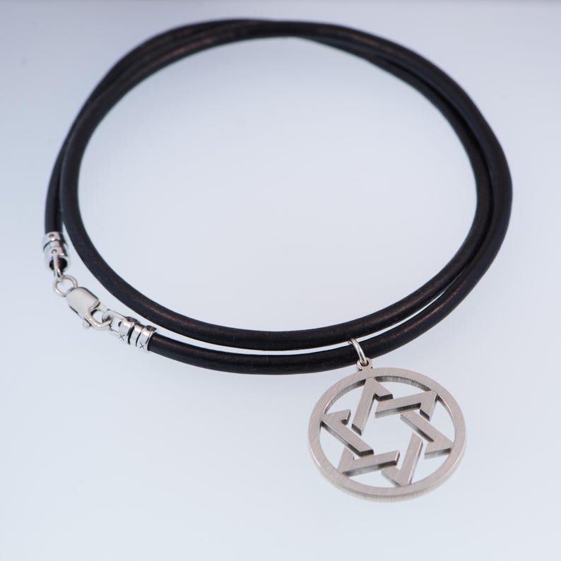 Pu&ograve; includere: Una collana in pelle nera con un ciondolo a forma di Stella di David color argento. Il ciondolo &egrave; una stella a sei punte all'interno di una cornice circolare. La collana ha una chiusura argentata.