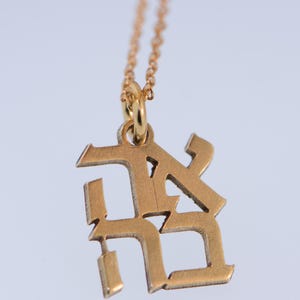 May include: A gold chain necklace with a gold pendant featuring the letters "RK" in a stylised font.