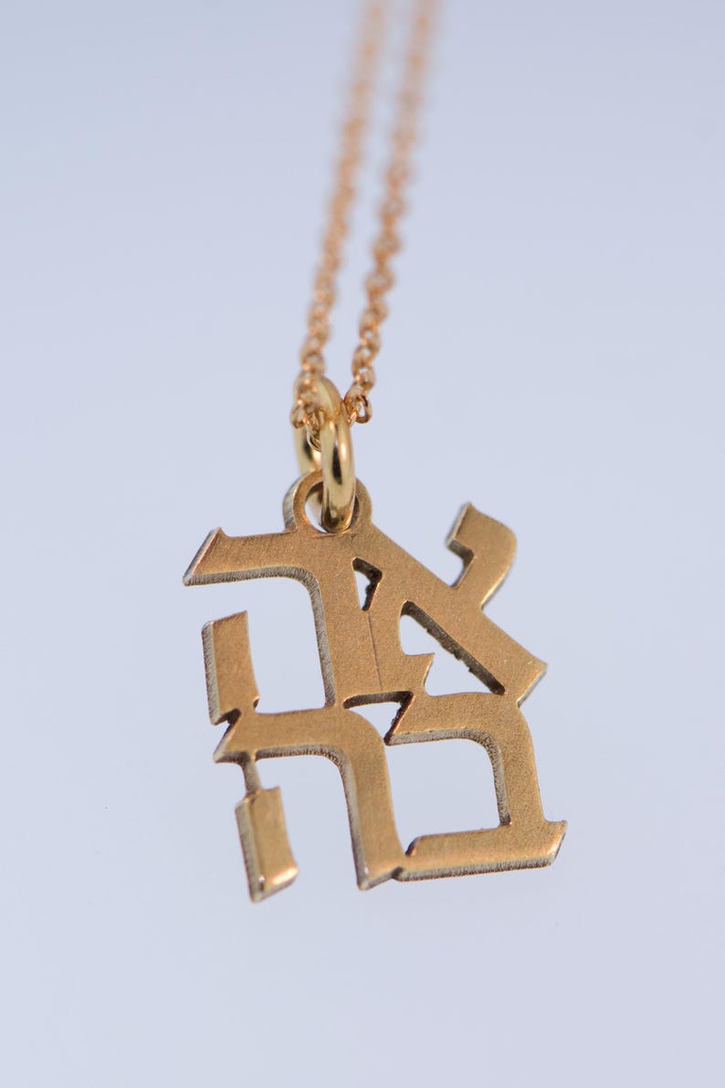 May include: A gold chain necklace with a gold pendant featuring the letters "RK" in a stylised font.