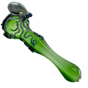 May include: A green glass pipe with an octopus design. The pipe features a green body with blue and gray accents, including an octopus head and tentacles. The design is detailed and artistic, with a smooth, glossy finish.