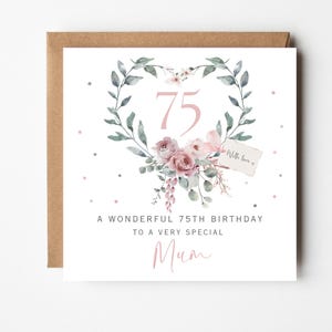 May include: A square greeting card with a kraft envelope featuring a heart-shaped wreath of green leaves and dusty pink roses. The number 75 is centered in pink. Text reads: A WONDERFUL 75TH BIRTHDAY TO A VERY SPECIAL Mum, with a small tag saying With love x.