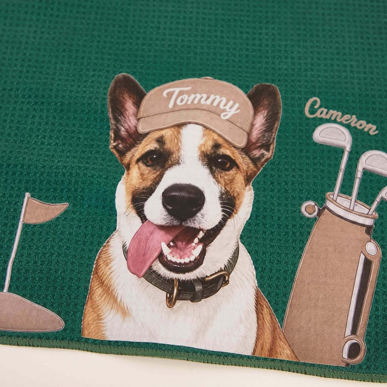 Puede incluir: Una toalla de color verde oscuro con textura de gofre que muestra un perro marr&oacute;n y blanco con una gorra beige con el nombre Tommy impreso. A la derecha, una bolsa de golf con el nombre Cameron impreso encima y una bandera de golf a la izquierda.