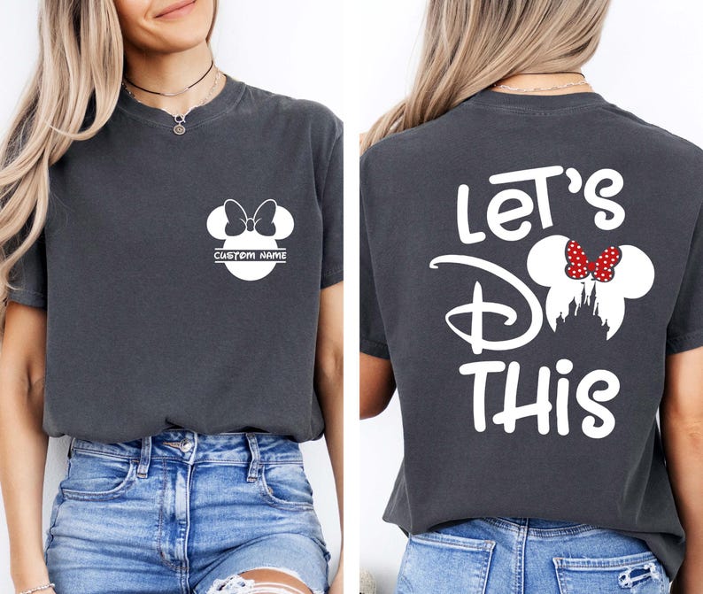 May include: Dark gray t-shirt featuring a white Minnie Mouse design with a bow and the text "CUSTOM NAME" on the front. The back of the shirt displays the text "Let's Do This" with a Minnie Mouse design and a red bow. The shirt is paired with blue denim shorts.