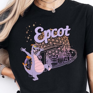 May include: Black t-shirt with a purple dragon and the text "Epcot" in a purple and orange font. The dragon is standing in front of a stylized image of the Spaceship Earth attraction at Epcot.