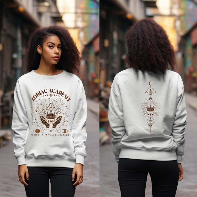 May include: White sweatshirt with a brown graphic print of a crown, hands, and celestial symbols. The text "Zodiac Academy Almighty Sovereign Society" is printed on the front of the sweatshirt.