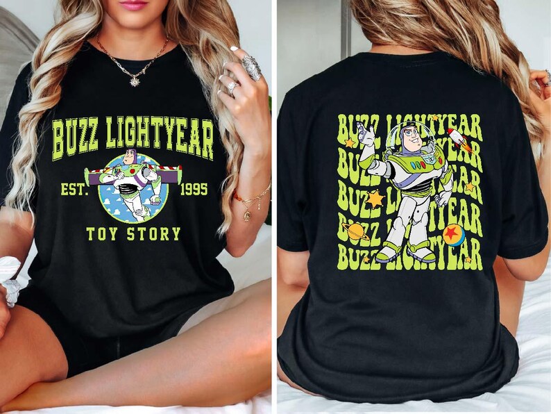 K&ouml;nnte beinhalten: Schwarzes T-Shirt mit einem gr&uuml;nen und gelben Grafikdruck von Buzz Lightyear aus Toy Story. Der Text "Buzz Lightyear" ist in einem gelben Bogen &uuml;ber dem Charakter gedruckt. Der Text "Est. 1995" ist unter dem Charakter gedruckt. Der Text "Toy Story" ist unter dem Datum gedruckt.