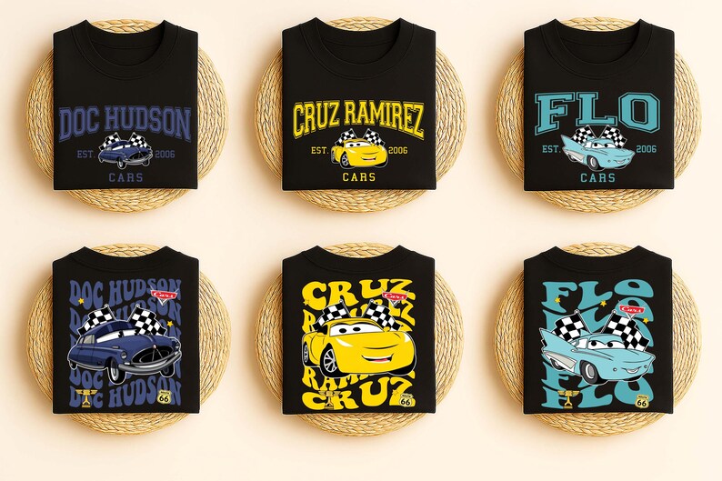 May include: Black t-shirts with car-themed graphics. Each shirt displays a different character's name, including "Doc Hudson," "Cruz Ramirez," and "Flo," alongside the year "2006" and the word "Cars."