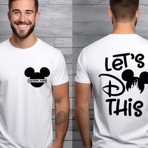 May include: White t-shirt featuring a black Mickey Mouse head design. The front has a customizable name area, and the back displays the text "Let's Do This" with a Mickey Mouse silhouette. A casual, everyday wear tee.
