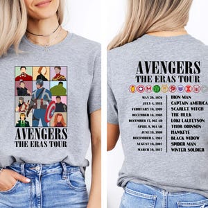 May include: Gray t-shirt with a graphic of the Avengers characters and the text "Avengers The Eras Tour". The back of the shirt has a list of the Avengers characters and their corresponding dates.