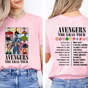 May include: Pink t-shirt with a graphic of the Avengers characters and the text "Avengers The Eras Tour". The back of the shirt lists the Avengers characters with their corresponding dates.