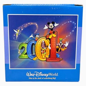 May include: A blue box featuring a colorful graphic of Disney characters, including Mickey Mouse, Donald Duck, and Goofy, celebrating "2001". The text "Walt Disney World" and "This is the start of something Big!" are also visible.