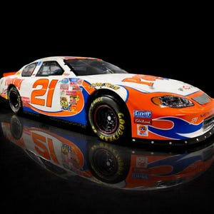 Op de afbeelding: Een witte, oranje en blauwe stock car met het nummer 21. De auto heeft sponsorstickers en Goodyear-banden. De auto wordt weerspiegeld in een glanzend zwart oppervlak.