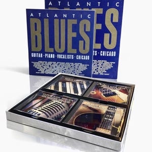 Könnte beinhalten: Eine Box mit Atlantic Blues CDs. Die Box ist blau mit goldfarbenen Buchstaben, die "Atlantic Blues" lauten. Im Inneren sind vier CDs zu sehen, die Bilder von Klavier, Gitarre und Mikrofon zeigen. Das Set befindet sich in einem silbernen Etui.