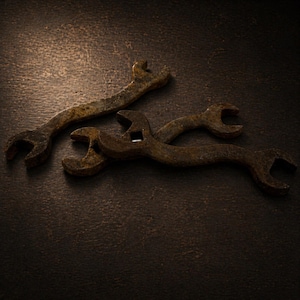 Peut inclure: Trois clés anglaises antiques et rouillées de différentes tailles sont disposées sur une surface sombre et texturée. Les clés ont un aspect vieilli, avec des signes visibles d'âge et d'utilisation. Les outils sont probablement utilisés pour les réparations mécaniques ou la construction.