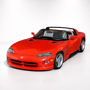 Puede incluir: Un coche deportivo rojo brillante con techo descapotable. El coche tiene un diseño elegante con ruedas plateadas y una silueta baja. La parte delantera presenta una parrilla y faros distintivos. El coche está sobre un fondo blanco.