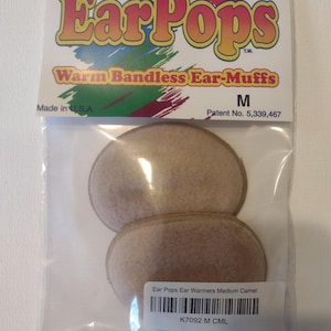 May include: A pair of camel-colored Ear Pops warmers in a plastic bag. The bag has the text "Ear Pops Warm Bandless Ear-Muffs" and "Made in USA". The bag also has a label that says "Ear Pops Ear Warmers Medium Camel K7092 M CML".