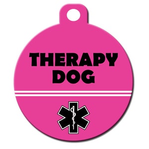 May include: Pink round dog tag with a white stripe and the text "THERAPY DOG" in black. A black and white medical symbol is below the text.