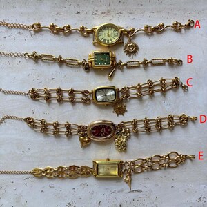 Pode incluir: Cinco pulseiras de rel&oacute;gio vintage douradas com diferentes mostradores e designs de corrente. Cada rel&oacute;gio tem um formato de mostrador &uacute;nico e &eacute; adornado com berloques, incluindo cora&ccedil;&otilde;es, s&oacute;is e uvas. Os rel&oacute;gios est&atilde;o rotulados de A a E.